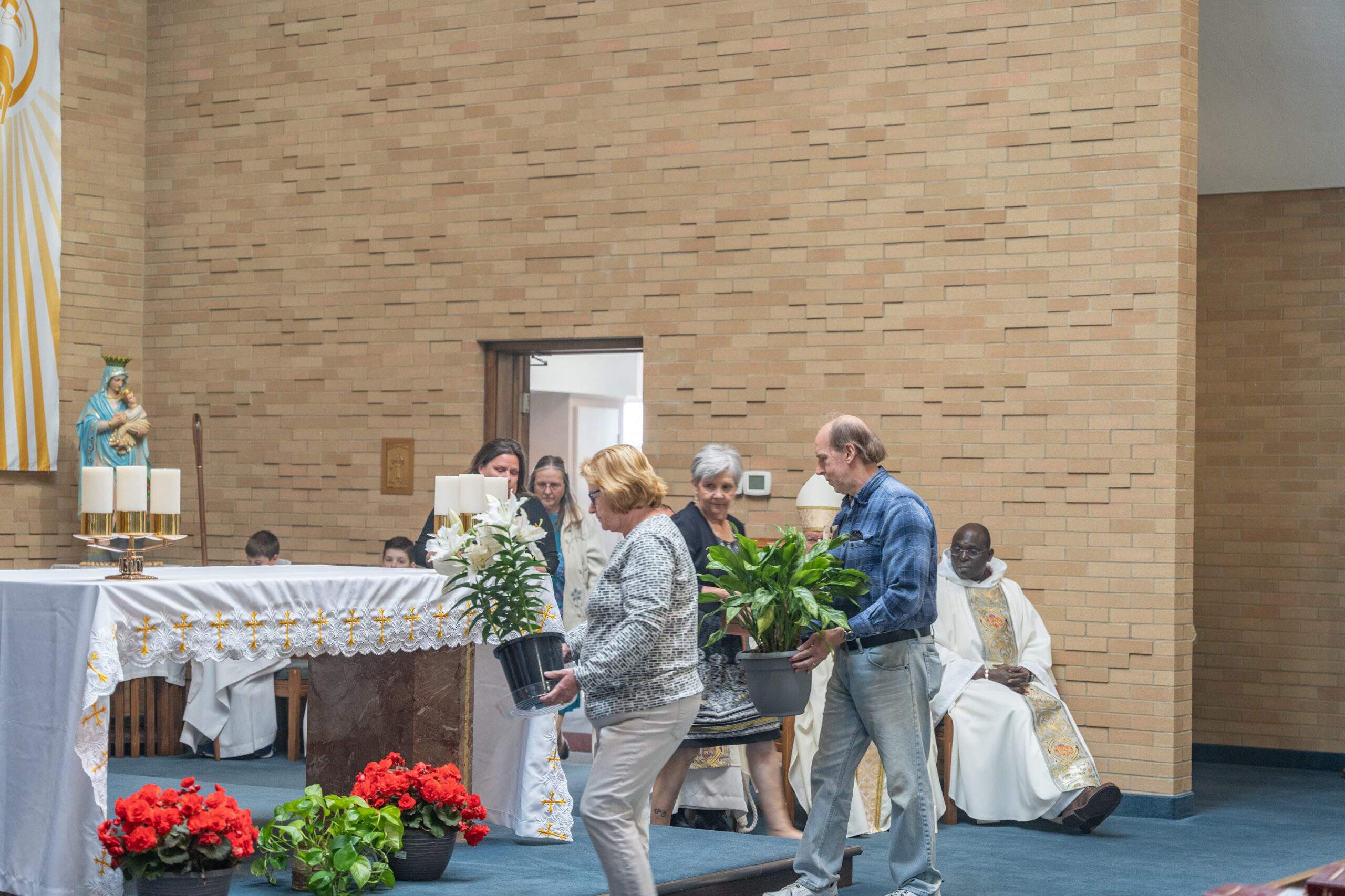Parishioners bring forward flowers to decorate the altar at St. Mary Parish in Orwell. Photo by Brian Keith