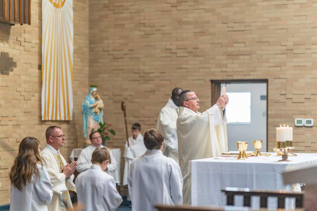 Bishop Bonnar says the Eucharistic prayers, surrounded by kneeling altar servers at St. Mary's in Orwell. Photo by Brian Keith