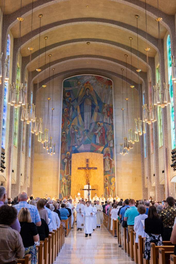 Priests and servers walk in procession out of the church.