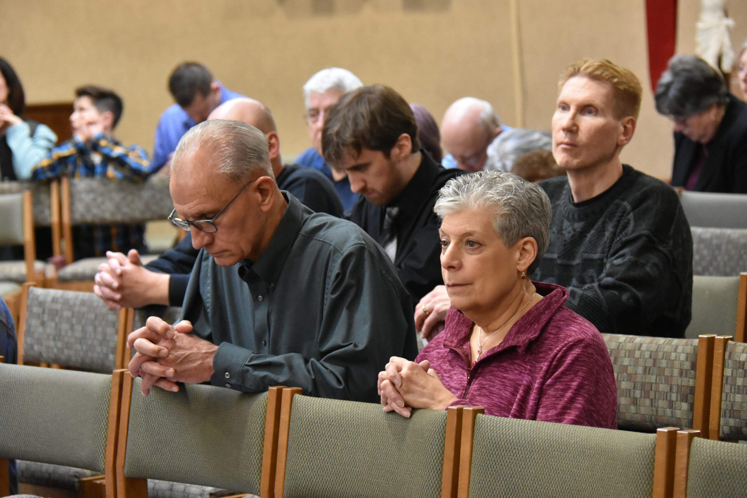 Older couple praying the rosary together in church