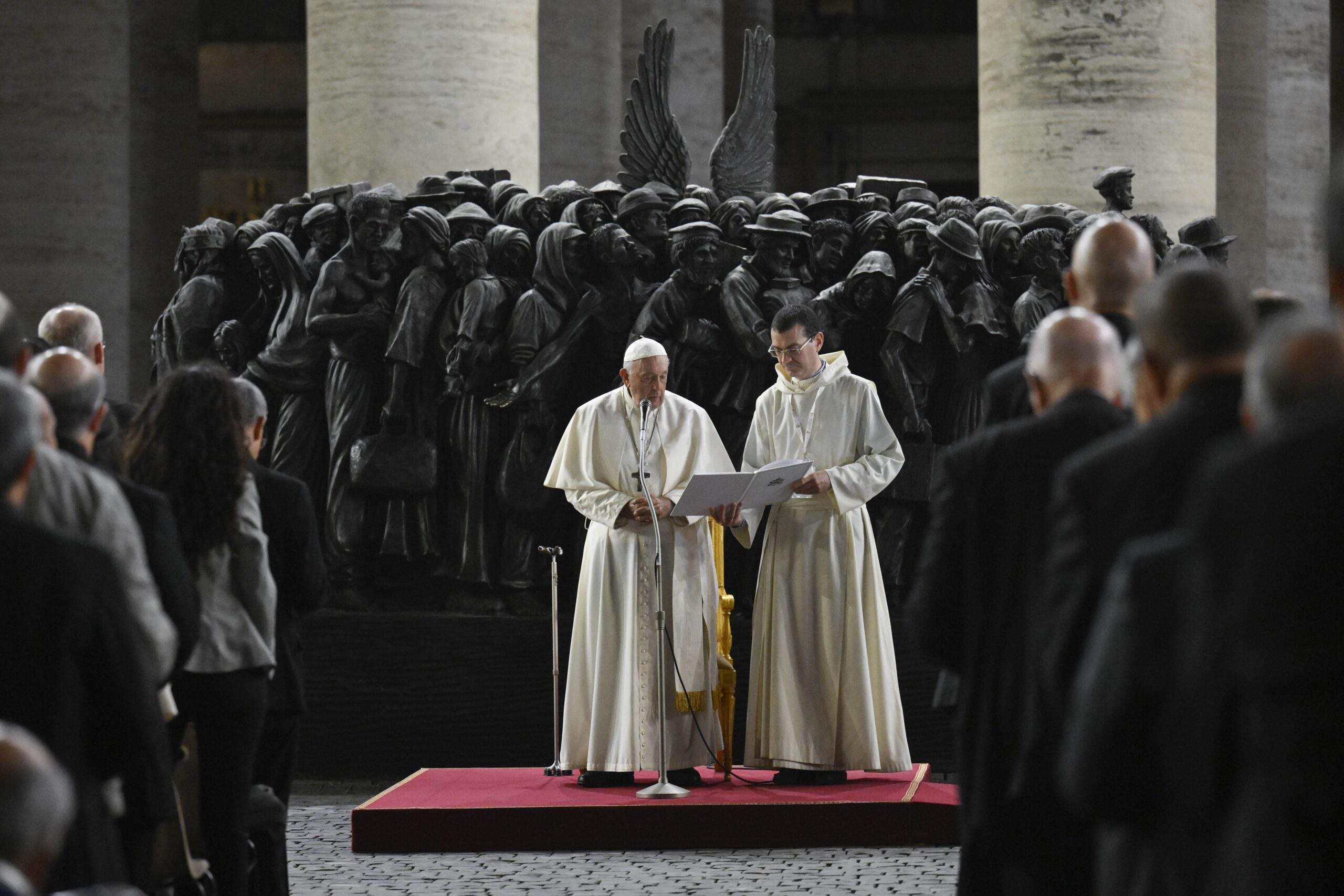 Pope Francis leads members of the assembly of the Synod of Bishops in praying for migrants and refugees in front of the statue, "Angels Unawares," in St. Peter's Square Oct. 19, 2023. The sculpture by Canadian Timothy Schmalz, depicts a boat with 140 figures of migrants from various historical periods and various nations. (CNS photo/Vatican Media)