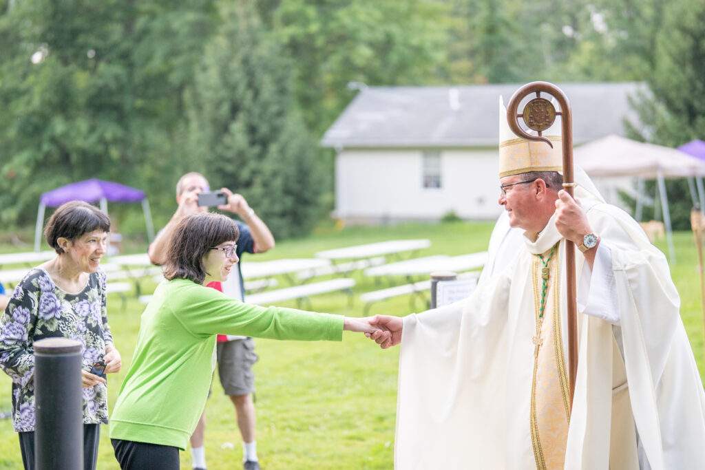 Bishop shakes young woman's hand after Mass
