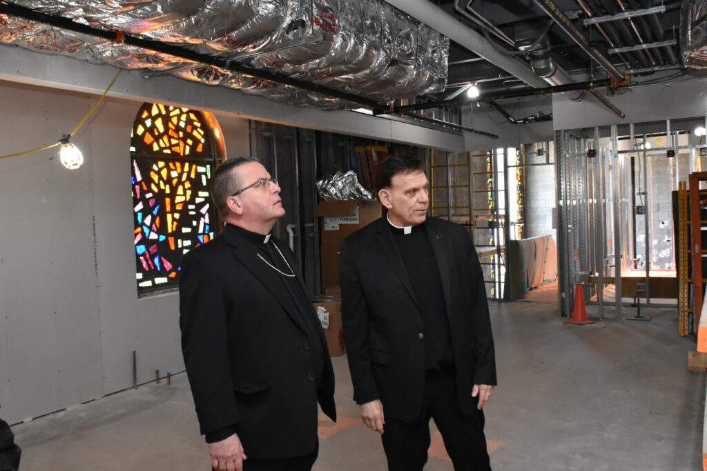 Bishop Bonnar and Father Sweirz stand in a construction zone.