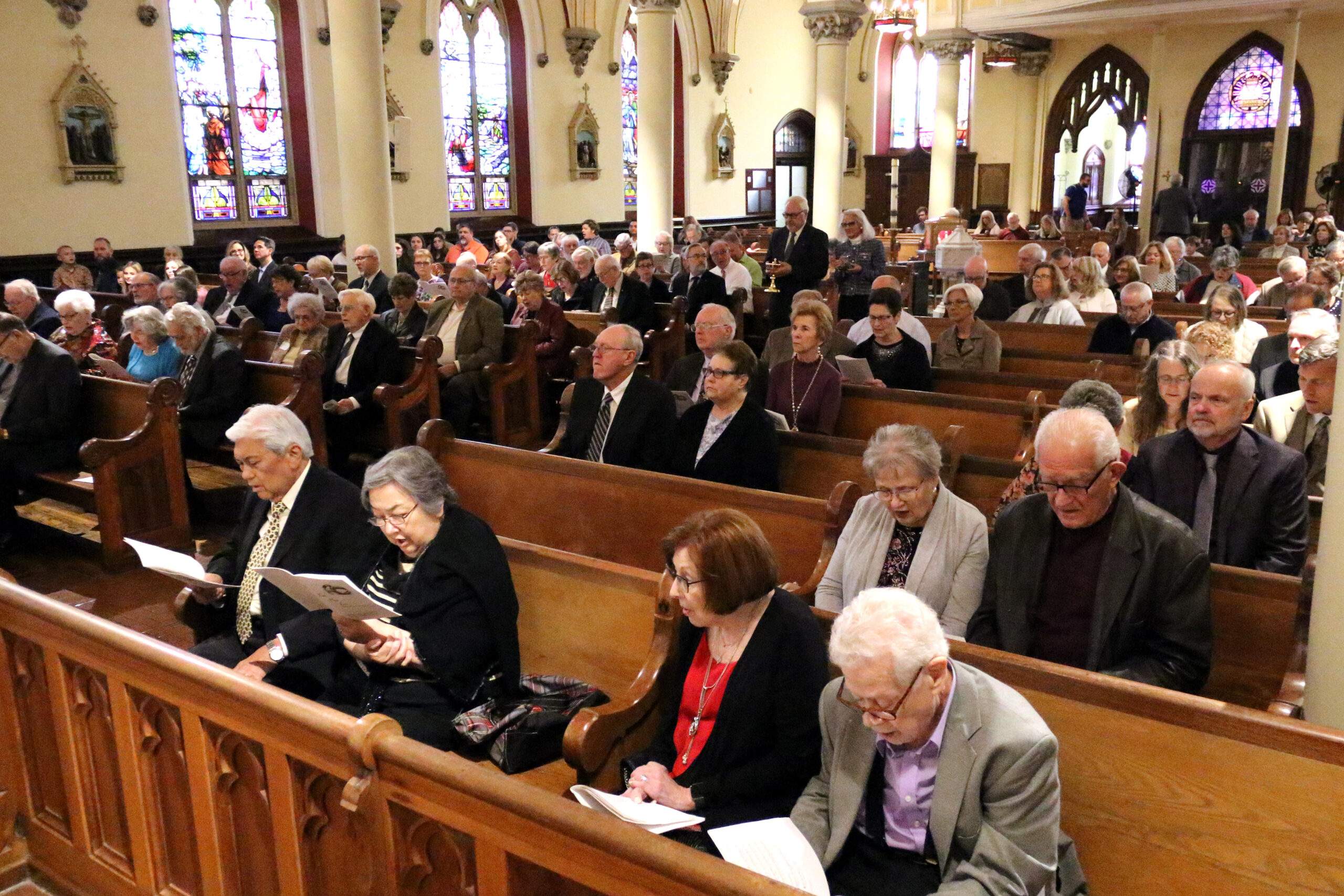 Parishioners sing from worship aids during Mass at St. John the Baptist Basilica