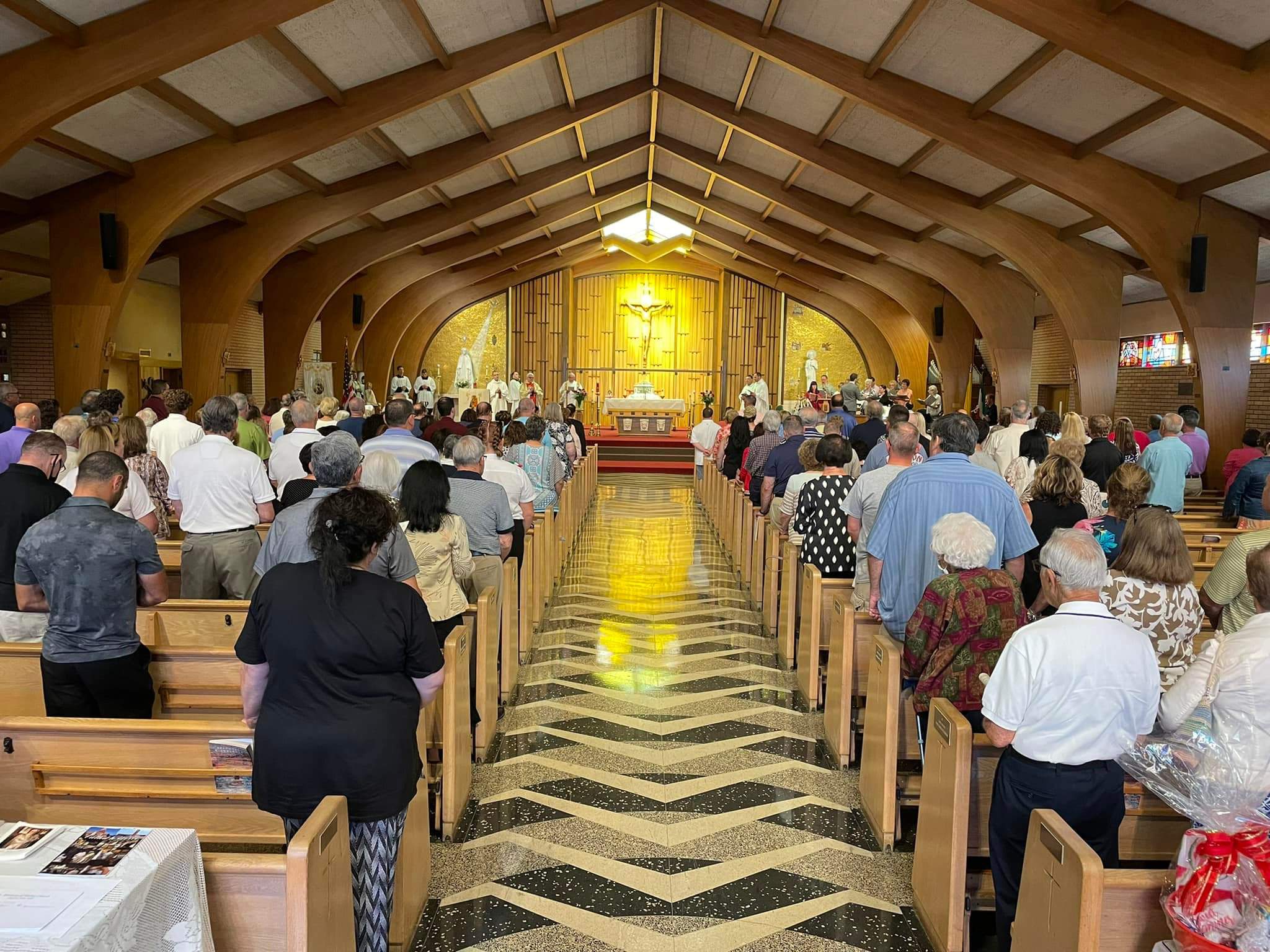 Parishioners stand at Mass. Angle is from the back of the sanctuary, in the center of the aisle.