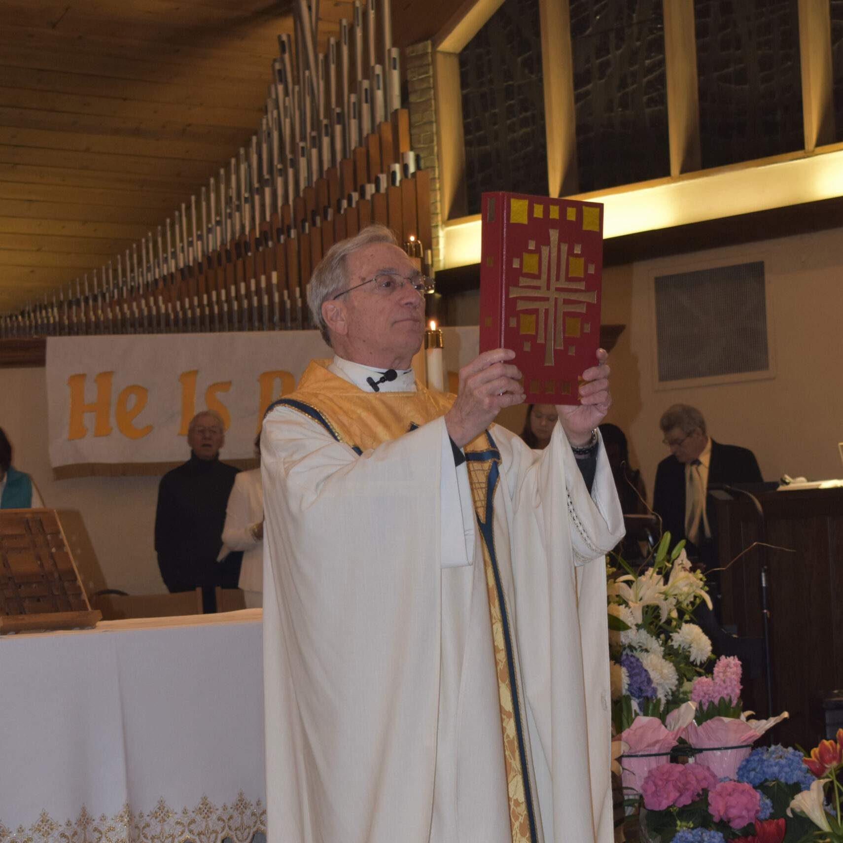 Very Reverend Raymond Thomas holds up bible during Mass.