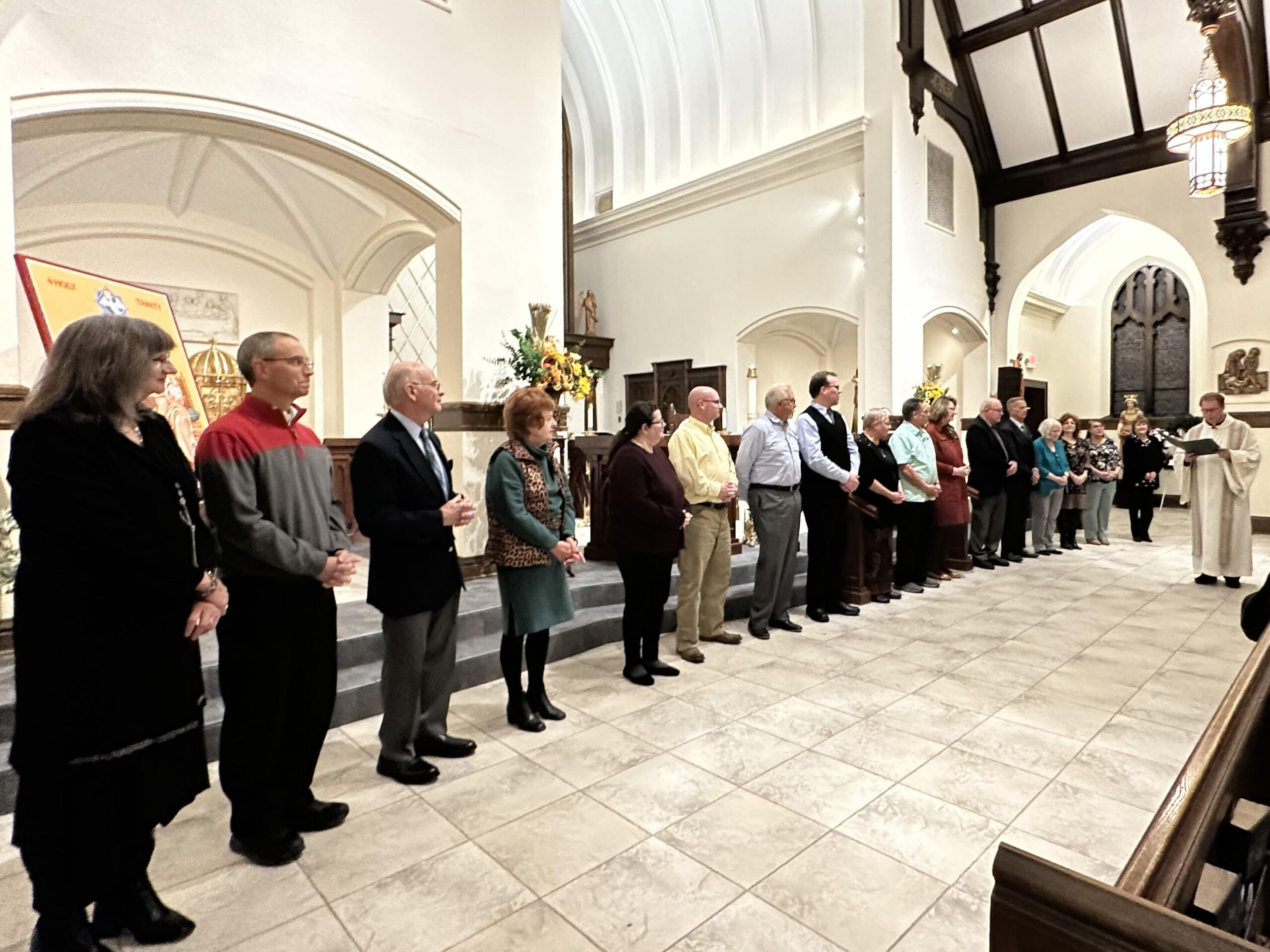 The lay leaders of prayer stand in front of the sanctuary while Father Michael Balash blesses them. 