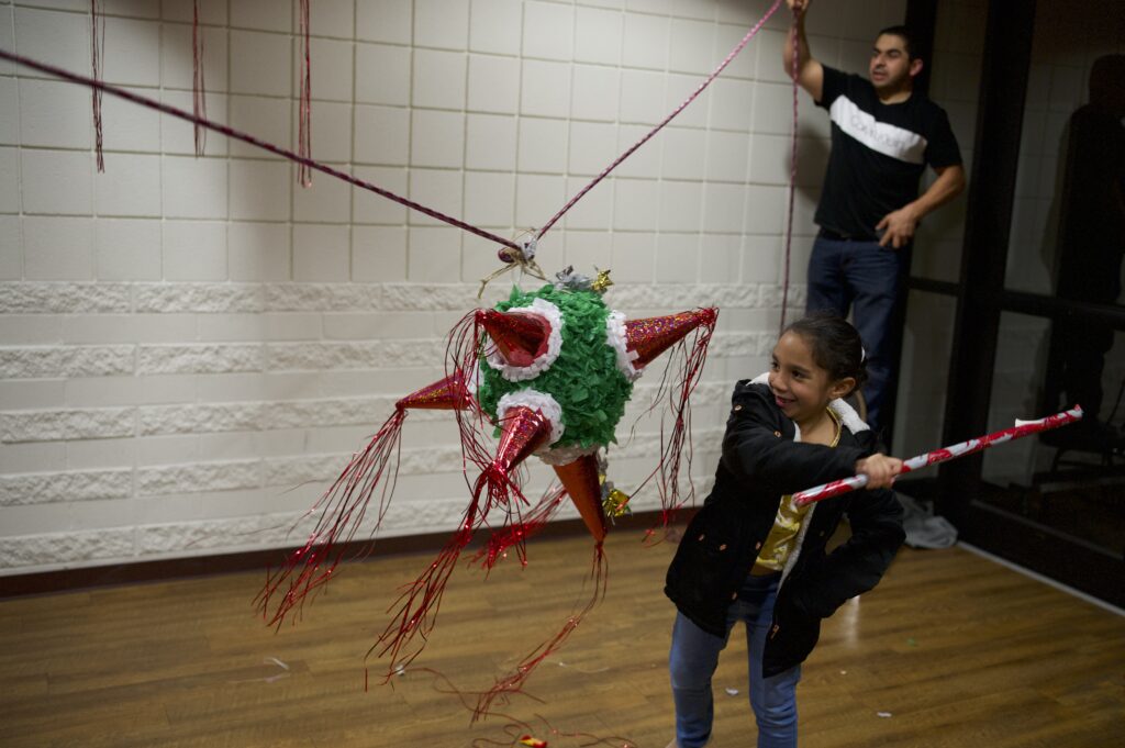 Young girl hits a piñata at Las Posadas celebration