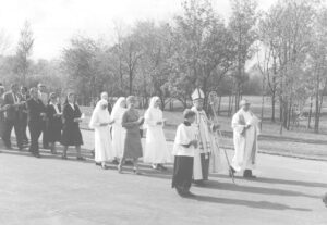 A group of religious and lay people process through Resurrection Cemetery behind bishop Franzetta.