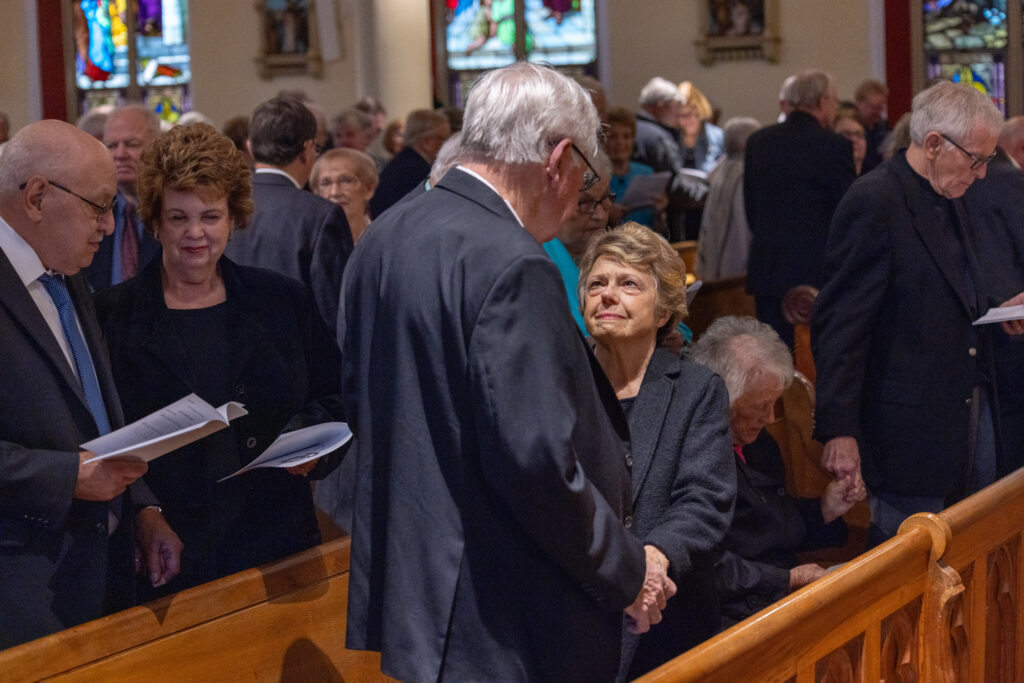 Couple holds hands in a pew while receiving a blessing at mass
