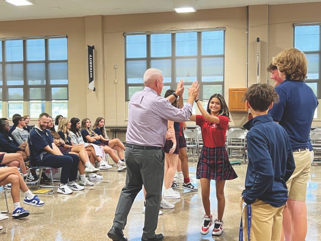 Student high-fives a teacher at an assembly