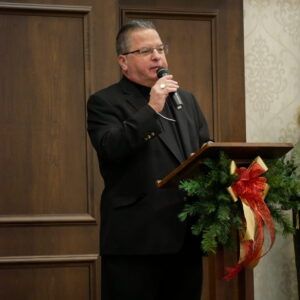 Bishop Bonnar stands at a podium with a wreath on it.