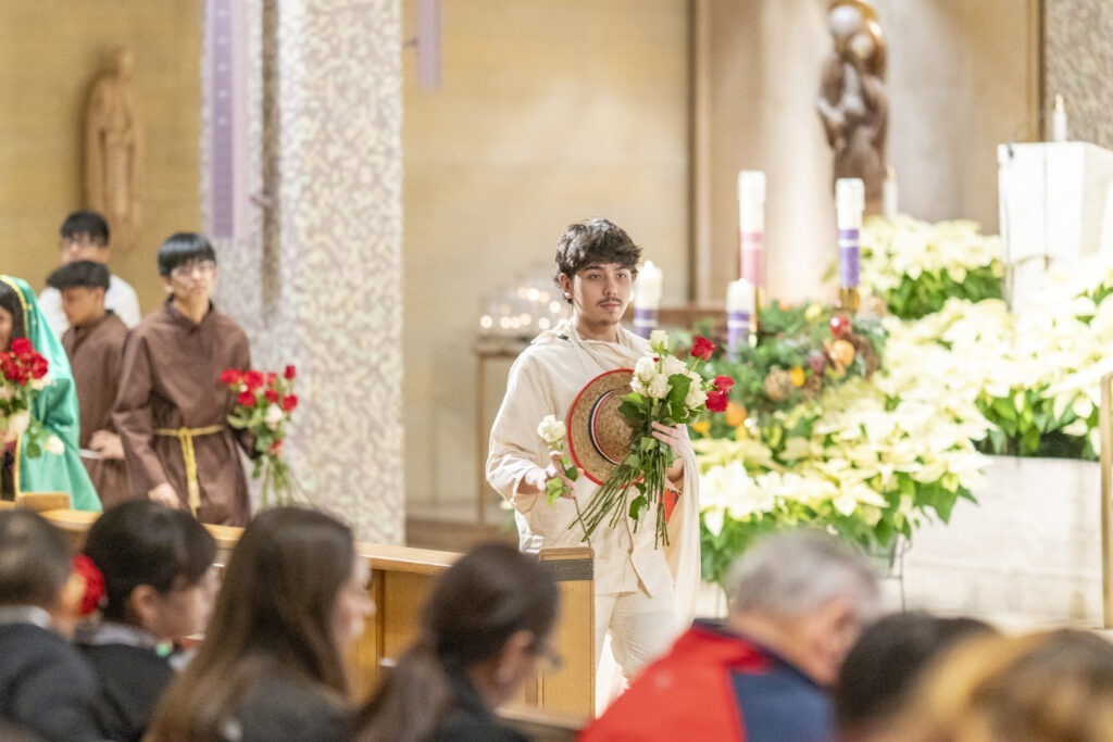 A man dressed as Juan Diego distributes flowers during the Our Lady of Guadalupe Mass
