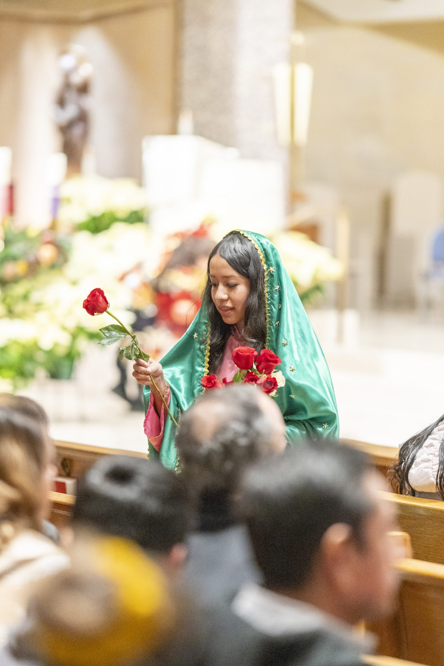 A woman dressed as Our Lady of Guadalupe distributes flowers at the 2023 Mass