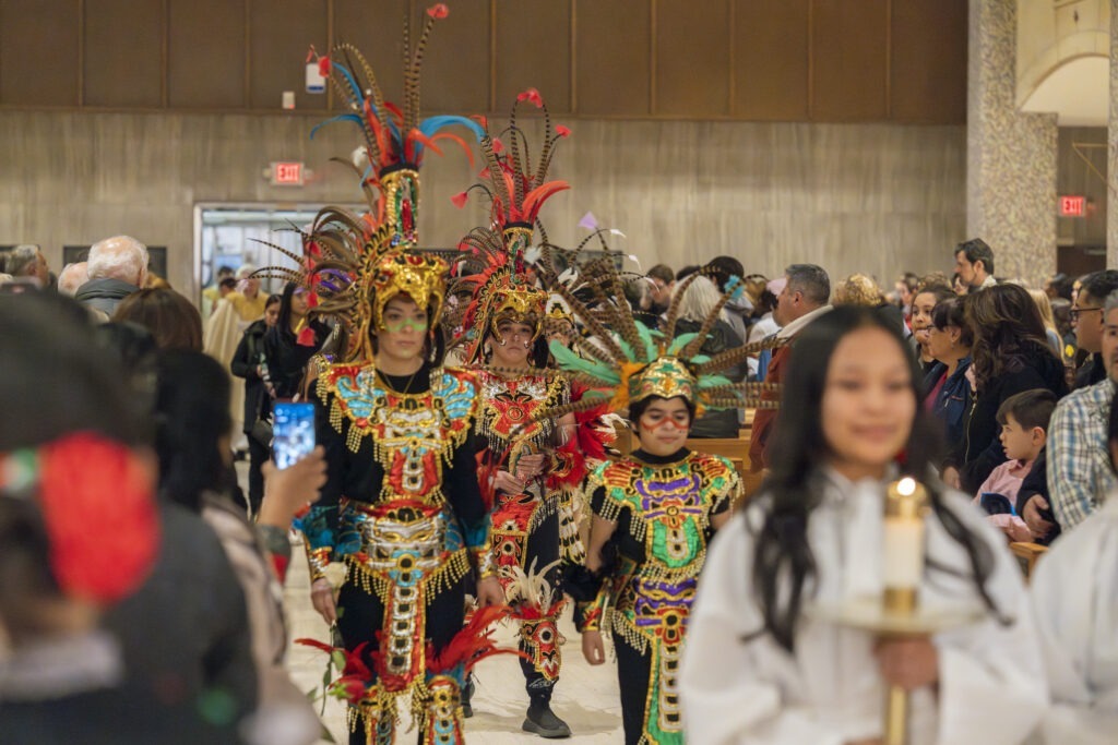 Costumed parishioners walk in procession during the Our Lady of Guadalupe Mass in 2023