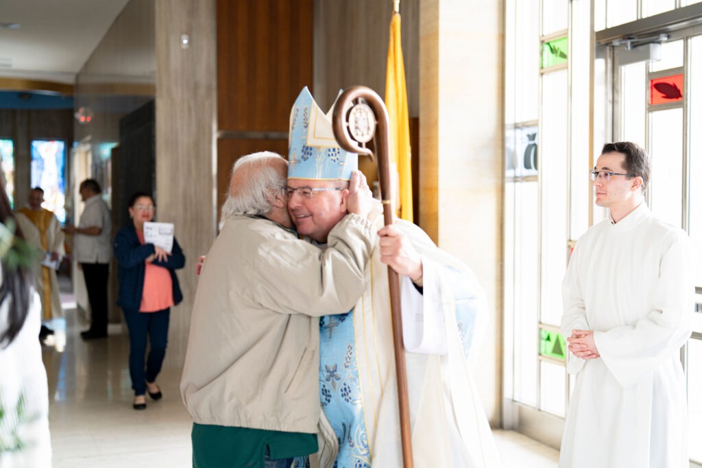 A parishioner hugs Bishop Bonnar at the end of the White Mass. Photo by Brian Keith