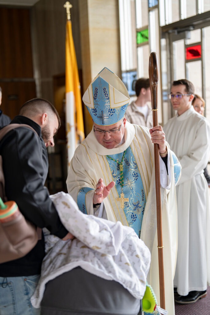 Bishop Bonnar blesses a baby after the annual White Mass. Photo by Brian Keith.