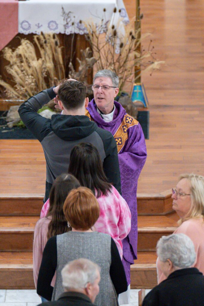 Father Leo Wehrlin administers ashes on Ash Wednesday at Holy Trinity Parish in East Liverpool.