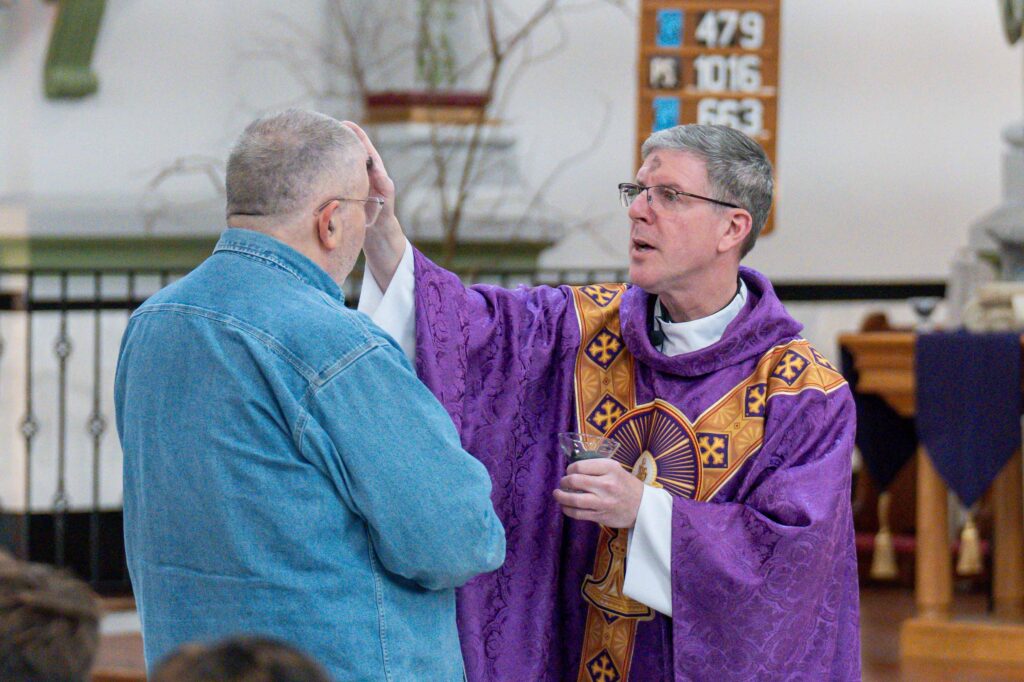Father Leo Wehrlin administers ashes at Holy Trinity Parish in East Liverpool on Ash Wednesday
