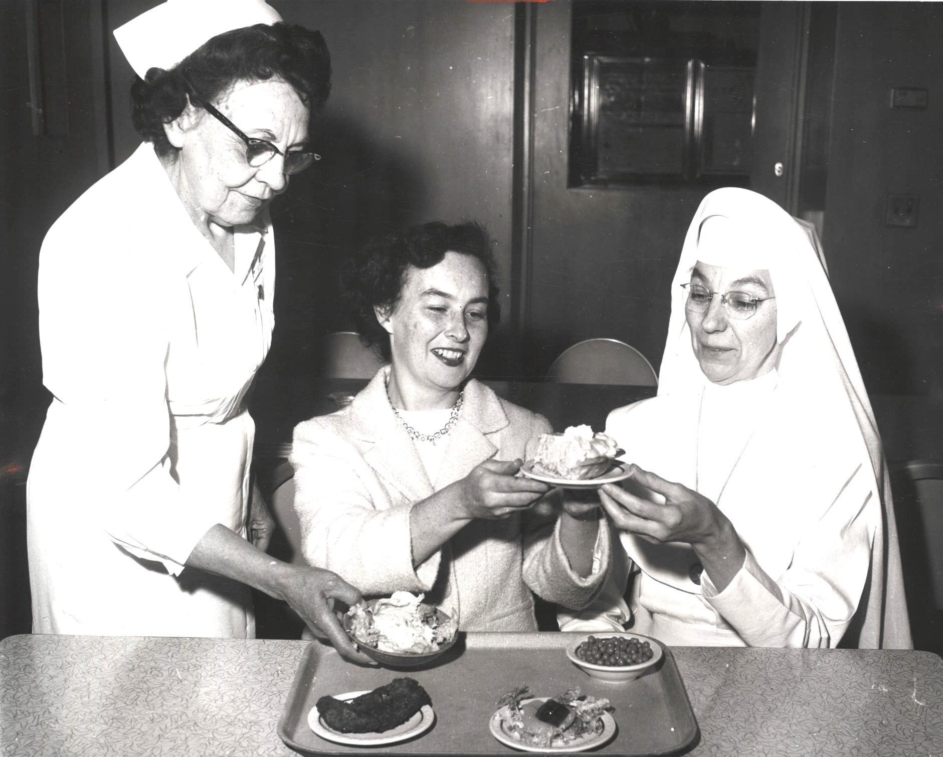 A nurse, nun and businesswoman examine food.