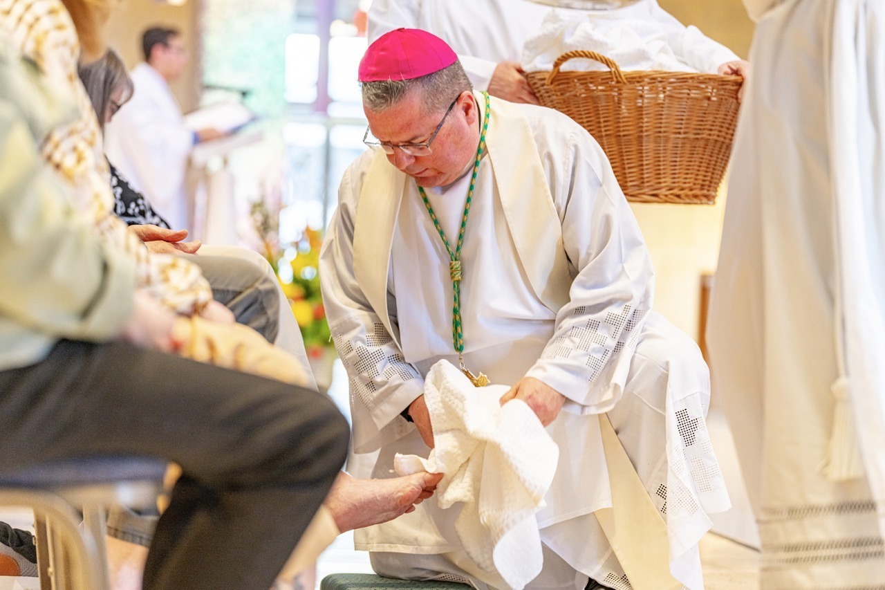 Bishop Bonnar uses a towel to dry a person's foot during Holy Thursday 2024. Photo by Brian Keith.