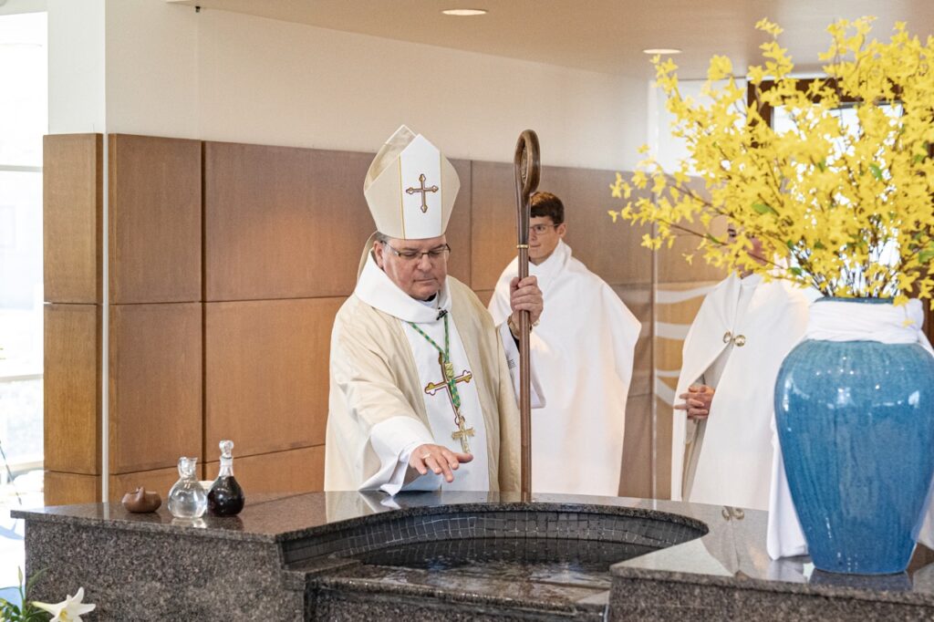 Bishop Bonnar blesses the holy water in the baptismal font at Blessed Sacrament. Photo by Brian Keith.