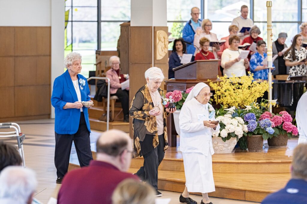 Three jubilarians bring up the gifts during Mass. Photo by Brian Keith. 