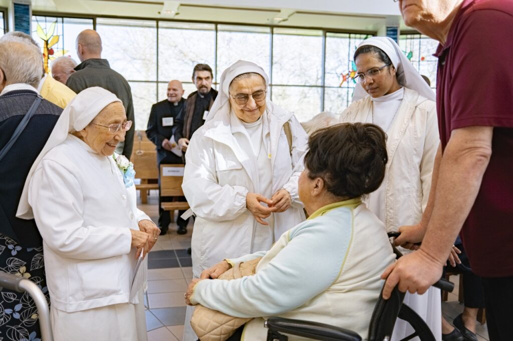 Three oblate sisters greet another sister in a wheelchair. Photo by Brian Keith. 