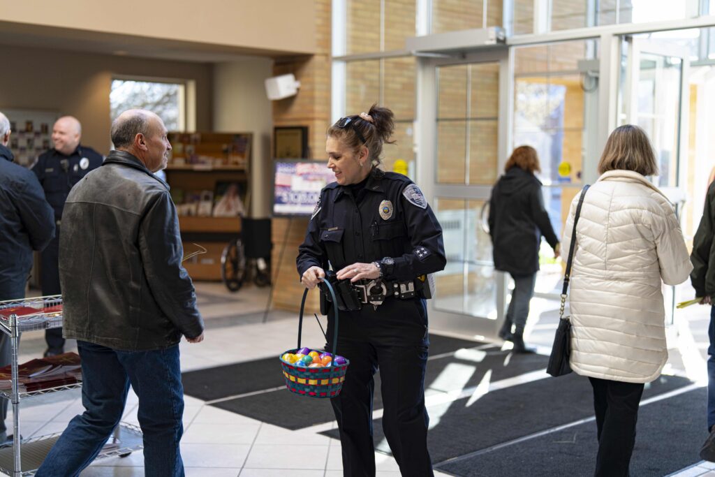 A police officer hands out easter eggs to parishioners after Mass. Photo by Brian Keith.