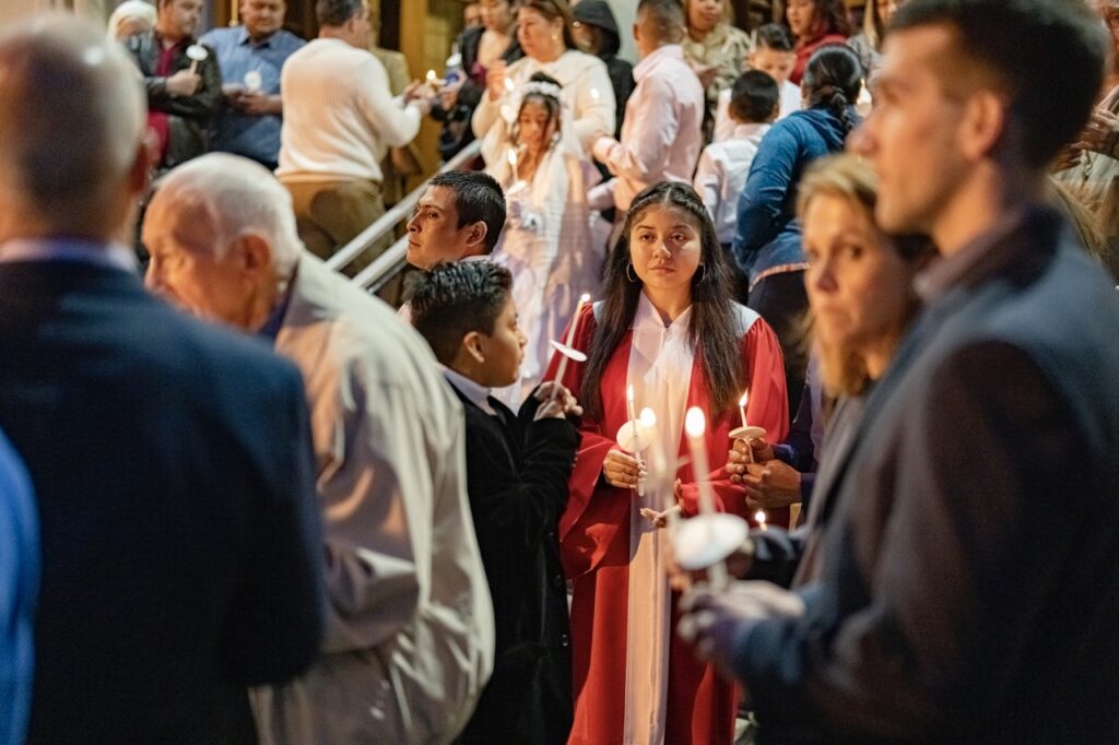 Confirmation candidate stands with her lit candle outside the church at the Easter Vigil 2024 at St. Dominic's. Photo by Brian Keith.