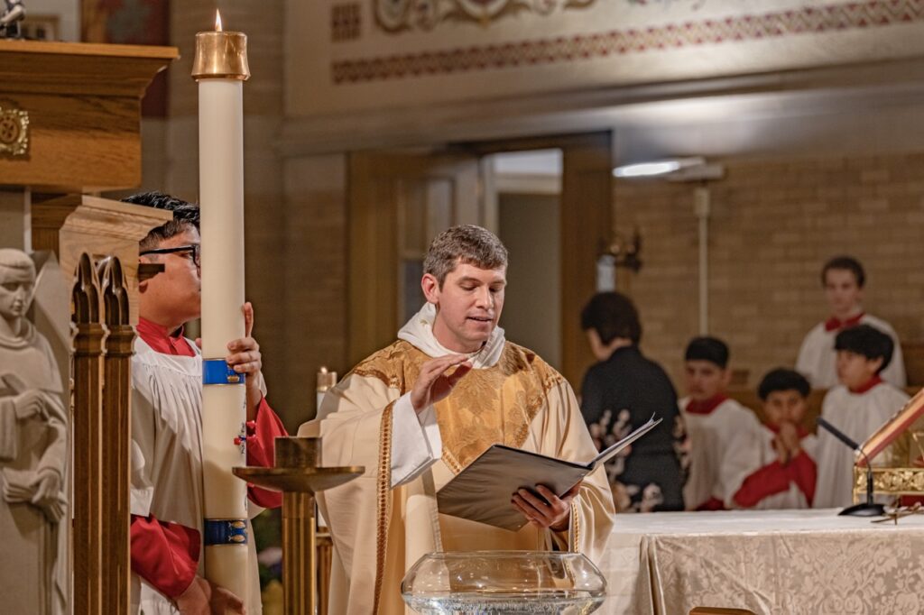 Priest reads baptismal rite at the Easter Vigil 2024 at St. Dominic's. Photo by Brian Keith.