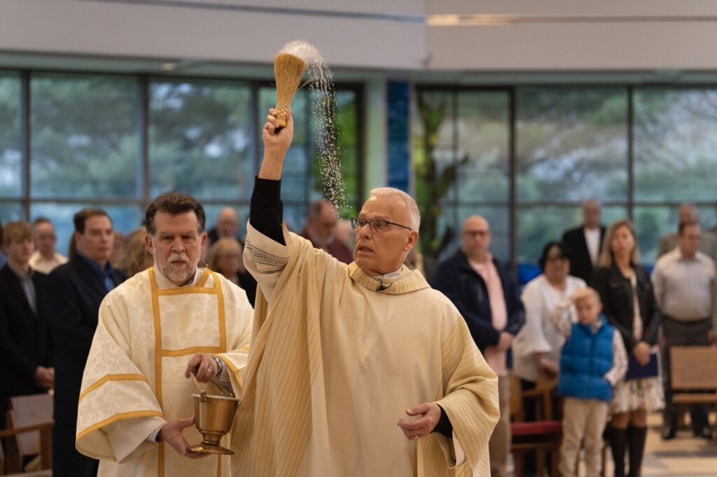 Priest blesses parishioners with holy water on Easter Sunday at Blessed Sacrament Parish in Warren. Photo by Brian Keith.