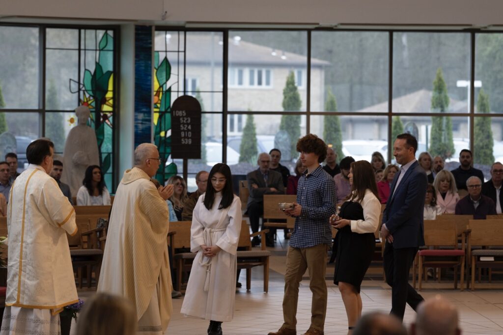 A young man and woman bring up the gifts on Easter Sunday at Blessed Sacrament Parish in Warren. Photo by Brian Keith.
