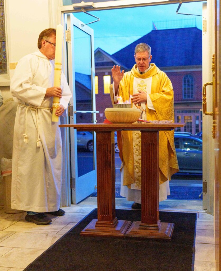 Priest blesses the Easter fire at the Easter Vigil 2024 at Holy Trinity Parish in East Liverepool. Photo by Jimmy Joe Savage.