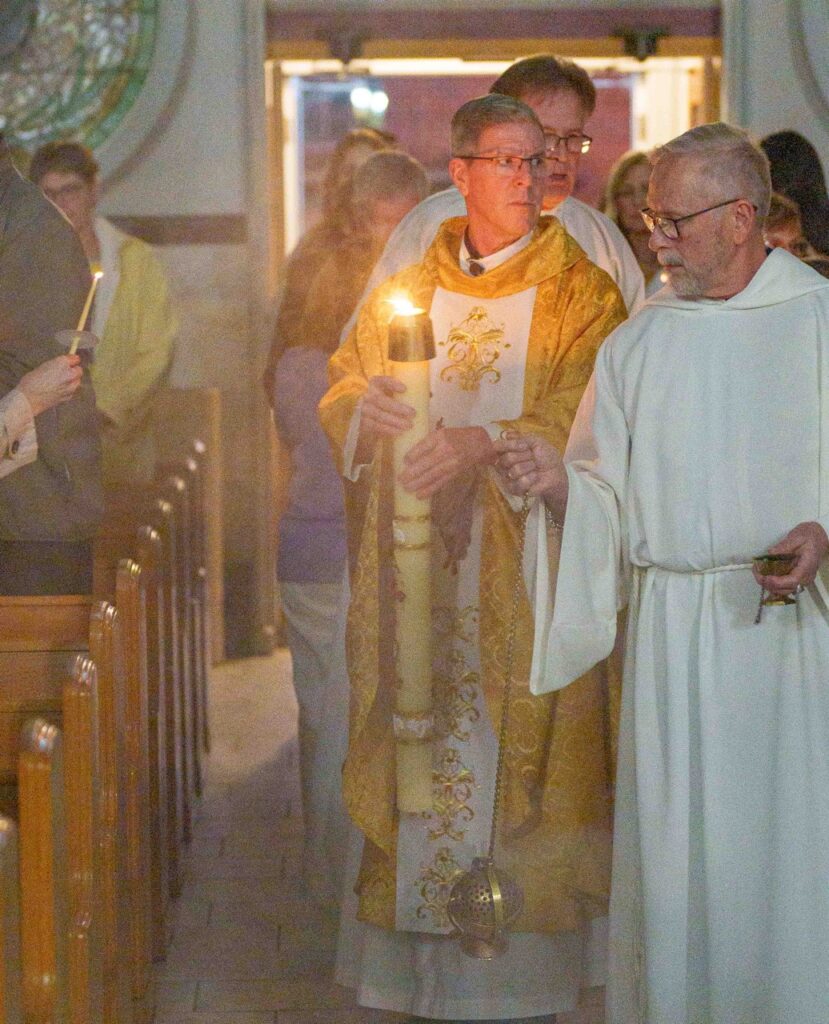 Priest holds the Easter Candle at the Easter Vigil 2024 at Holy Trinity Parish in East Liverepool. Photo by Jimmy Joe Savage.