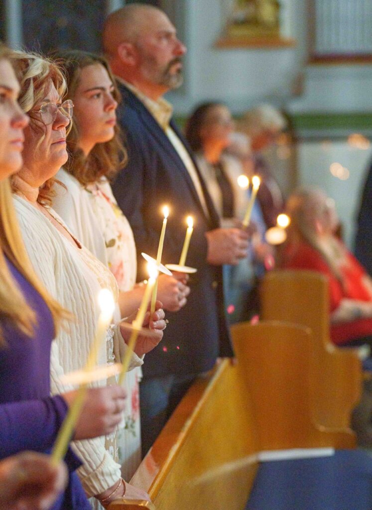 Parishioners stand, holding candles at the Easter Vigil 2024 at Holy Trinity Parish in East Liverepool. Photo by Jimmy Joe Savage.