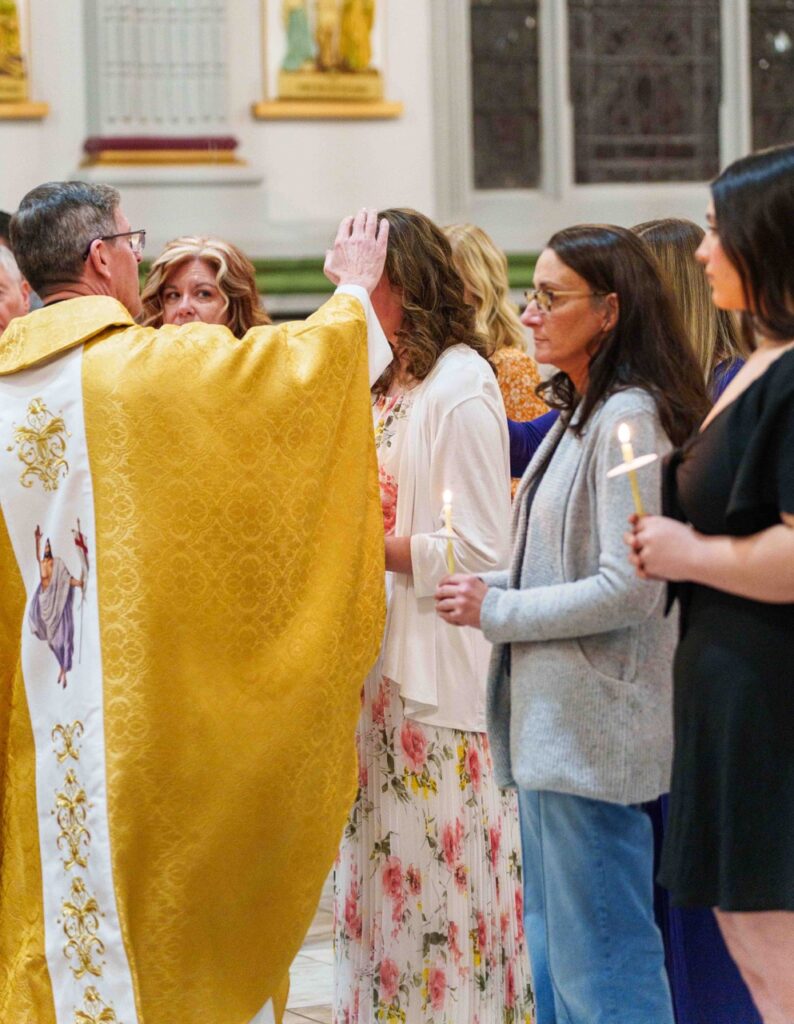 Priest confirms a candidate at the Easter Vigil 2024 at Holy Trinity Parish in East Liverepool. Photo by Jimmy Joe Savage.