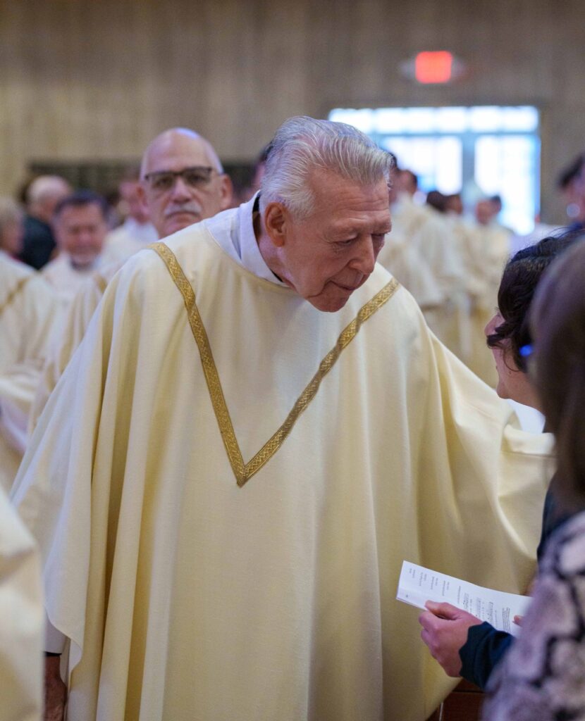 Priest stops to greet a parishioner. Photo by Jimmy Joe Savage. Chrism Mass 2024.