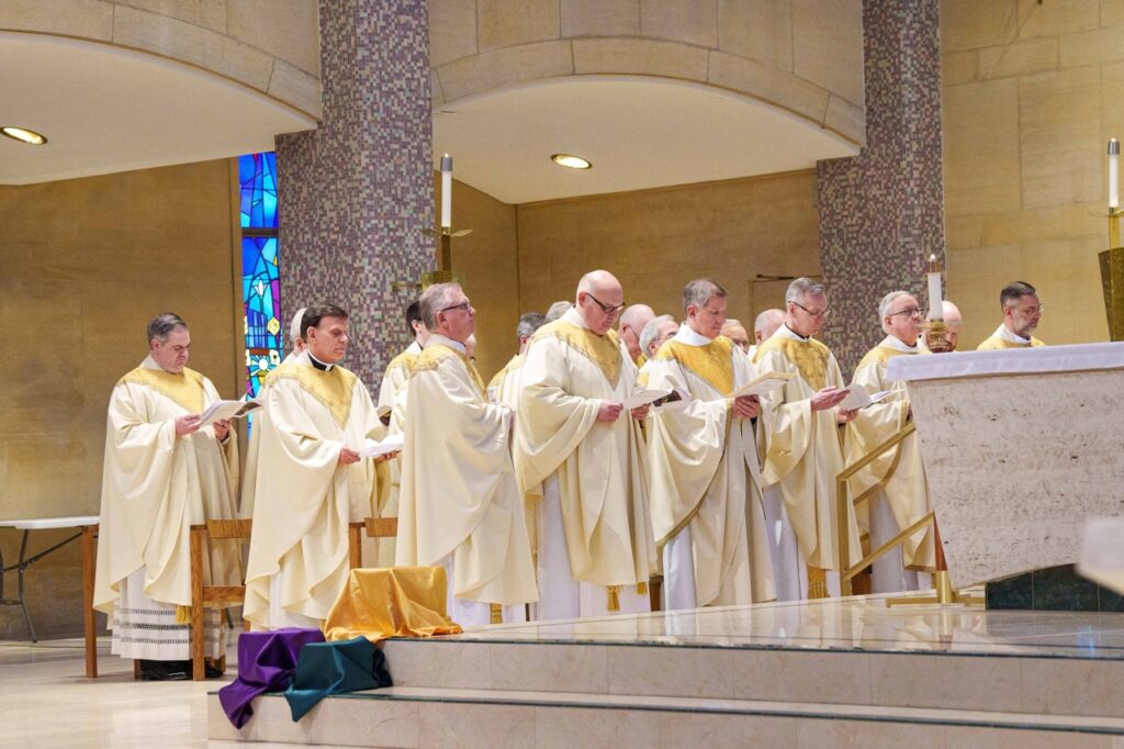 dozens of priests stand near the altar. Photo by Jimmy Joe Savage. Chrism Mass 2024.