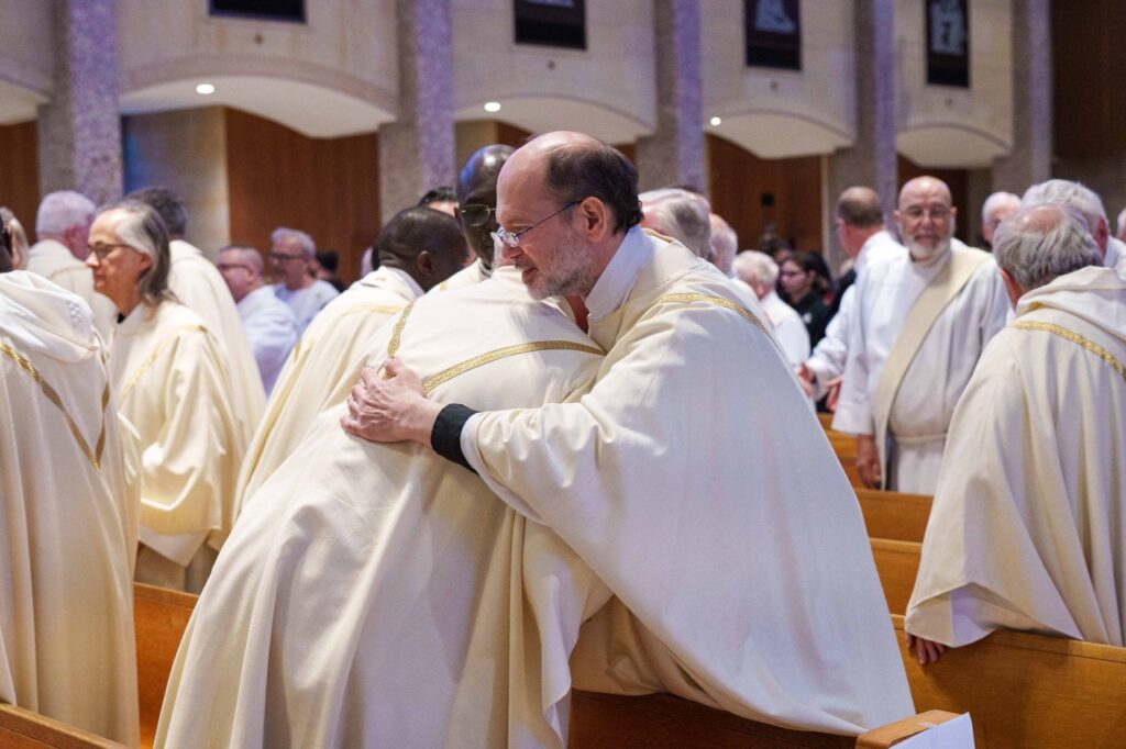 Priests offer greetings during the sign of peace. Photo by Jimmy Joe Savage. Chrism Mass 2024.