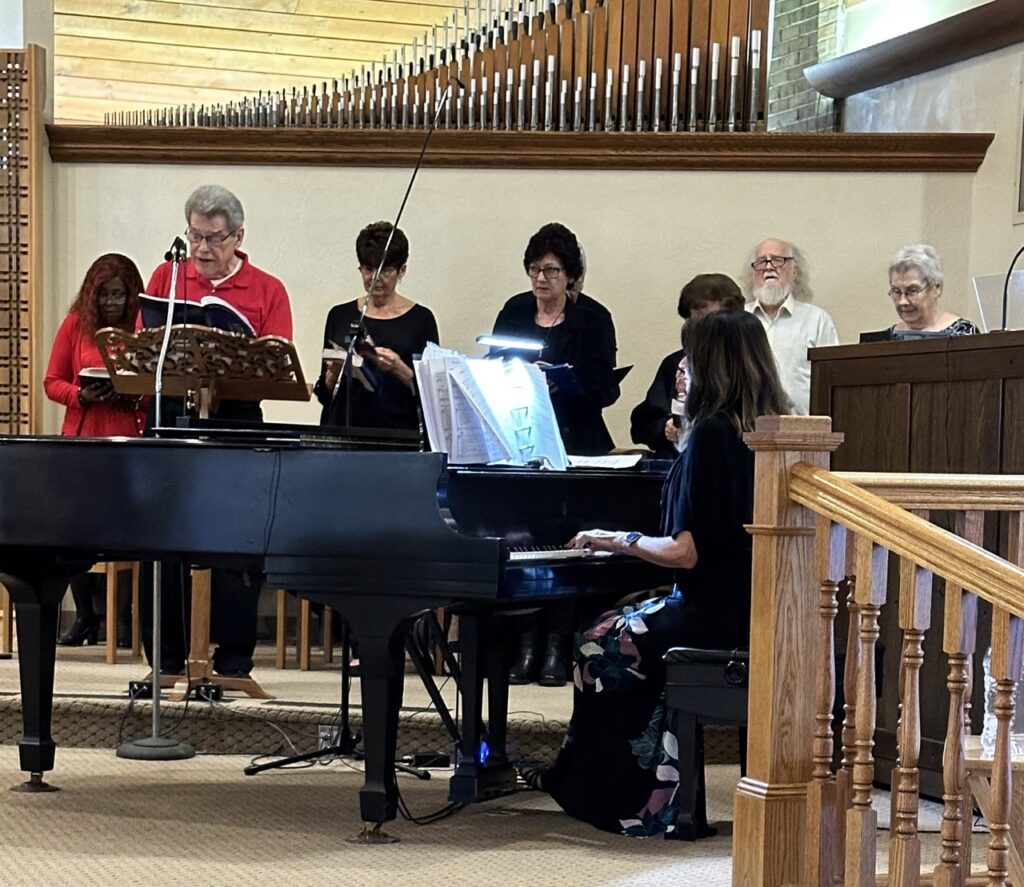 The choir stands around the piano and sings during the Good Friday Liturgy 2024 at Our Lady of Peace Parish in Ashtabula. Photo by Marilou McClimans.