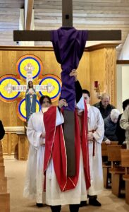 Father Thomas raises the cross, covered in a purple cloth at the Good Friday Liturgy 2024 at Our Lady of Peace Parish in Ashtabula. Photo by Marilou McClimans.