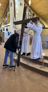 Man with a can leans forward to kiss the cross at the Good Friday Liturgy 2024 at Our Lady of Peace Parish in Ashtabula. Photo by Marilou McClimans.