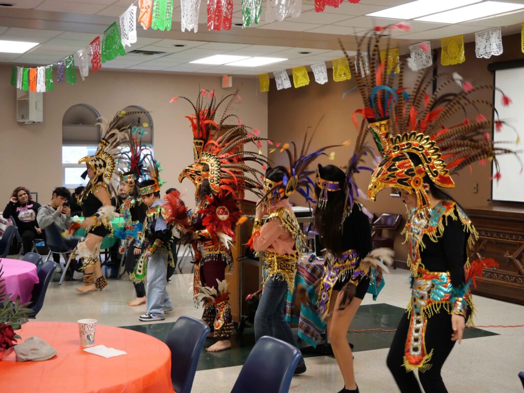 Members of the Hispanic community wear headdresses and dance at the second annual Hispanic summit