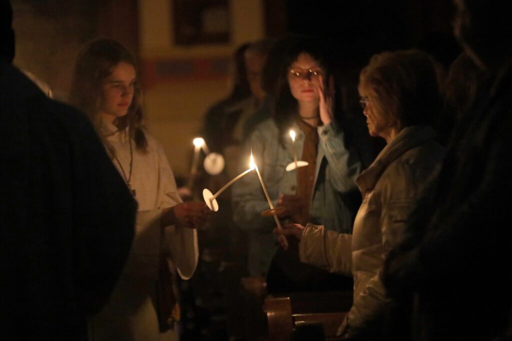 Female altar server lights congregants' candles at St. Joseph Parish in Mogadore during the Easter Vigil 2024. Photo by Ed Hall, Jr.