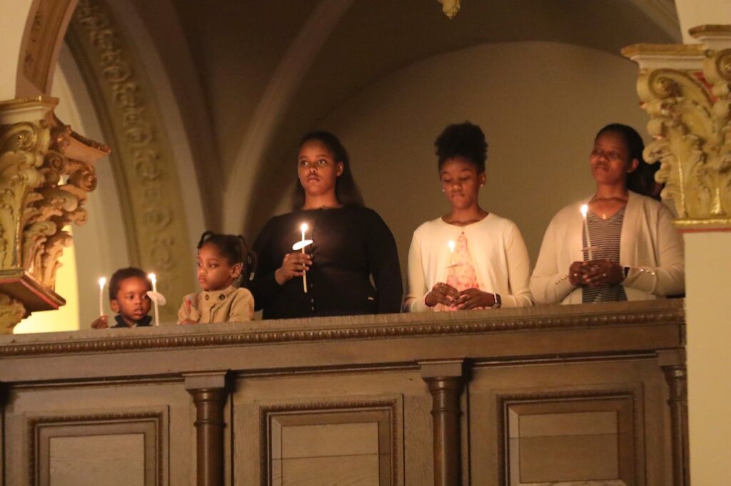 Young family hold their candles and look down from the balcony at St. Joseph Parish in Mogadore during the Easter Vigil 2024. Photo by Ed Hall, Jr.