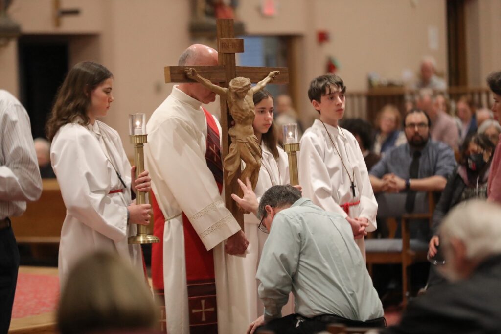 Man kneels in front of the cross at St. Paul Parish in North Canton on Good Friday 2024. Photo by Ed Hall, Jr.