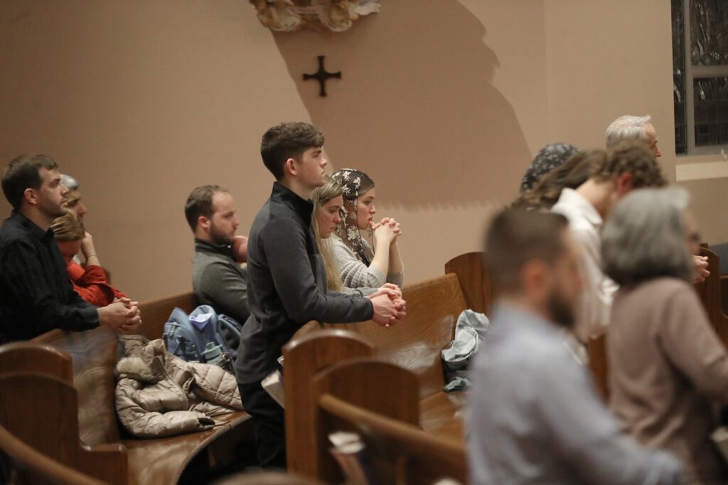 A young man and two women pray at St. Paul Parish in North Canton on Good Friday 2024. Photo by Ed Hall, Jr.