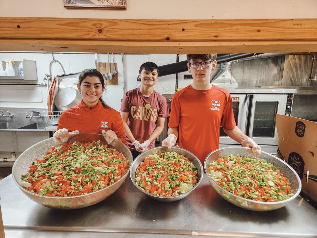 Three students show off the salads they made from their garden