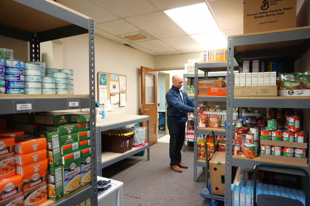 Man stocks food pantry shelves at Catholic Charities. Photo by Collin Vogt
